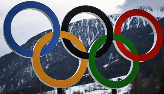 The Olympic rings in front of a snowy mountain in Italy.