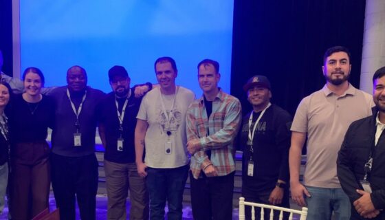 First cohort of the Military Datacenter Pathway-VETS pilot program posing in front of a blue screen.