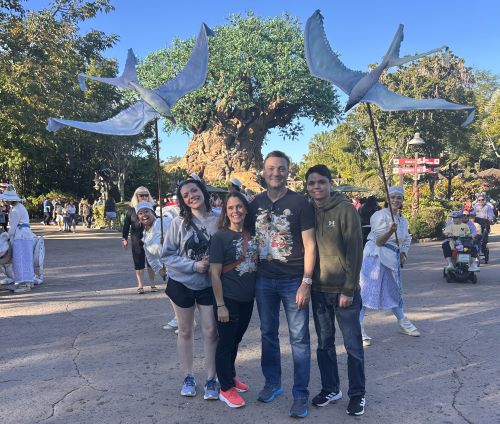 John Melendez and his family pose in front of two large birds on poles held by Disney employees.