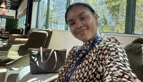 Lyric Green in professional attire sitting in an office building reception area.