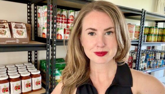 Close up of Megan Rowley standing in front of shelves of food at the JBAB food pantry.